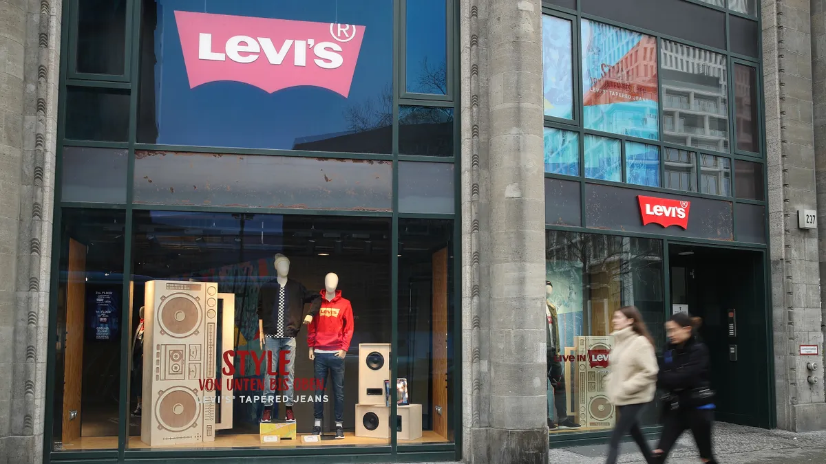 Two young women walk past a Levi's jeans and clothing store.