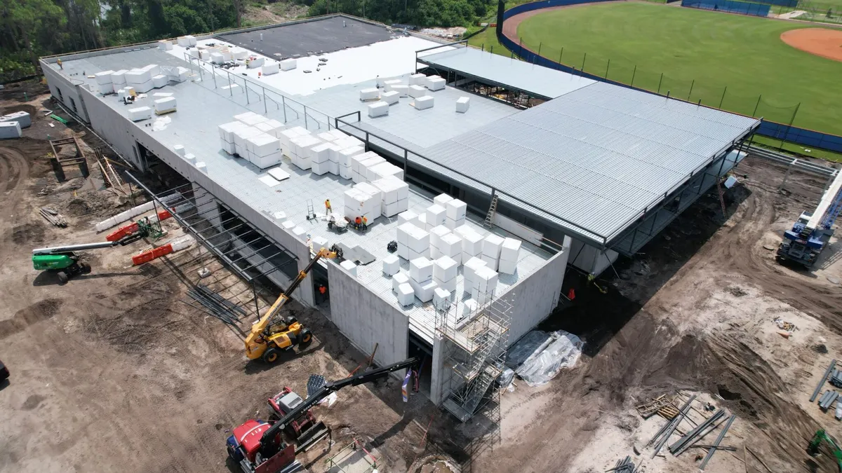 An aerial view of a blocky building on a dirt plot.