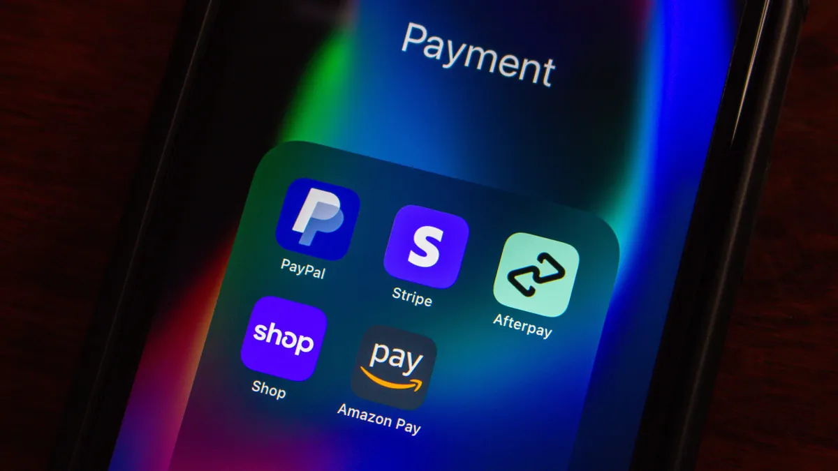 A smartphone screen displaying a folder labeled “Payment” with apps including PayPal, Stripe, Afterpay, Shop, and Amazon Pay, shown in a dark setting with colorful screen reflections.