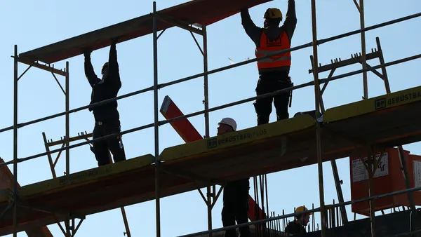 Workers set up scaffolding at the construction site of a new apartment building.
