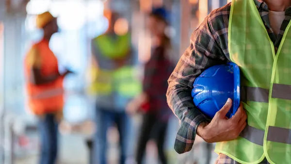 a construction work stands with his helmet in his hands