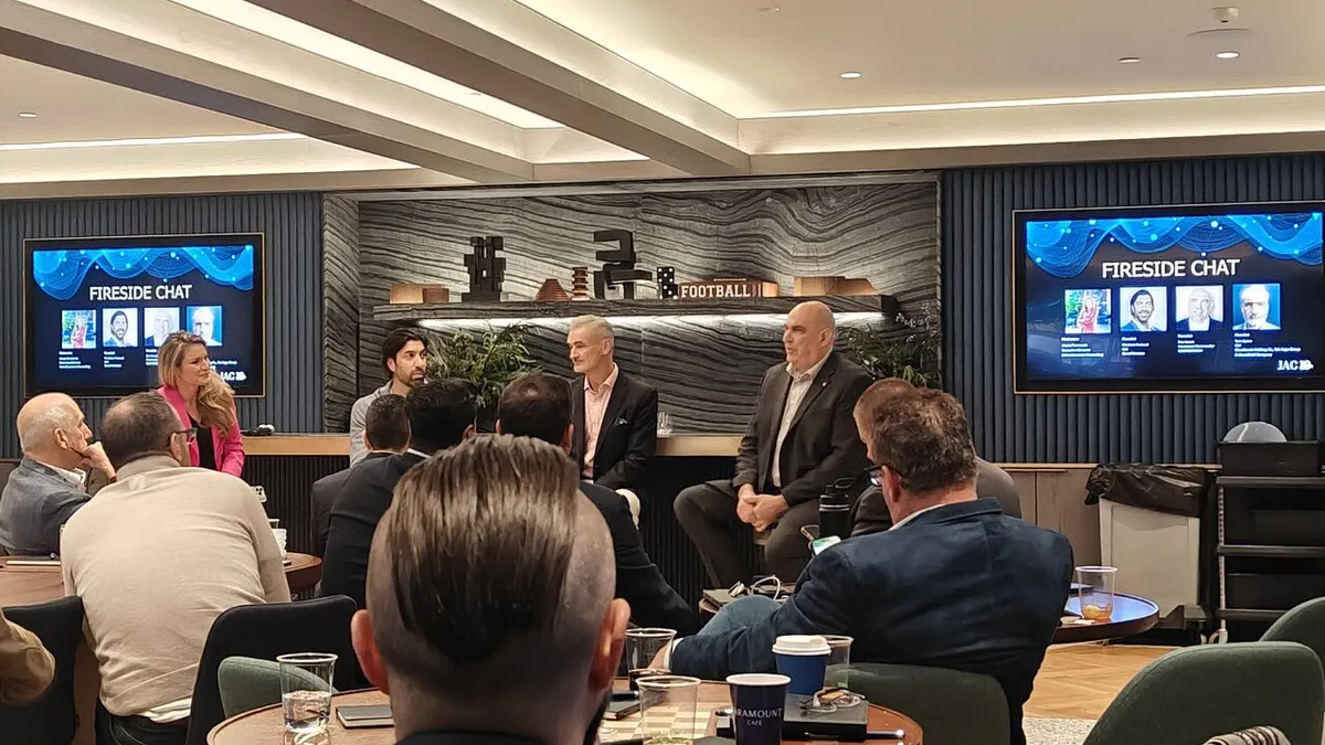 four-person panel in front of people who are seated at circular tables