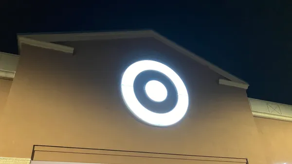 Target's white bullseye logo on a beige storefront at night.