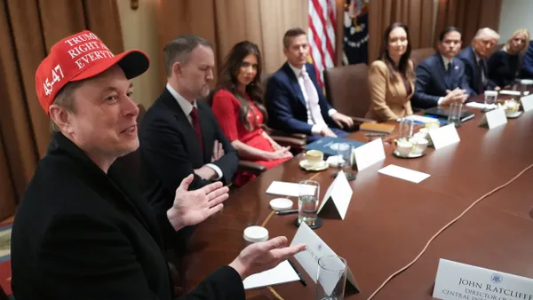 Man in red hat with a ball cap reading "Trump is right about everything" seated at a table with other men and women.