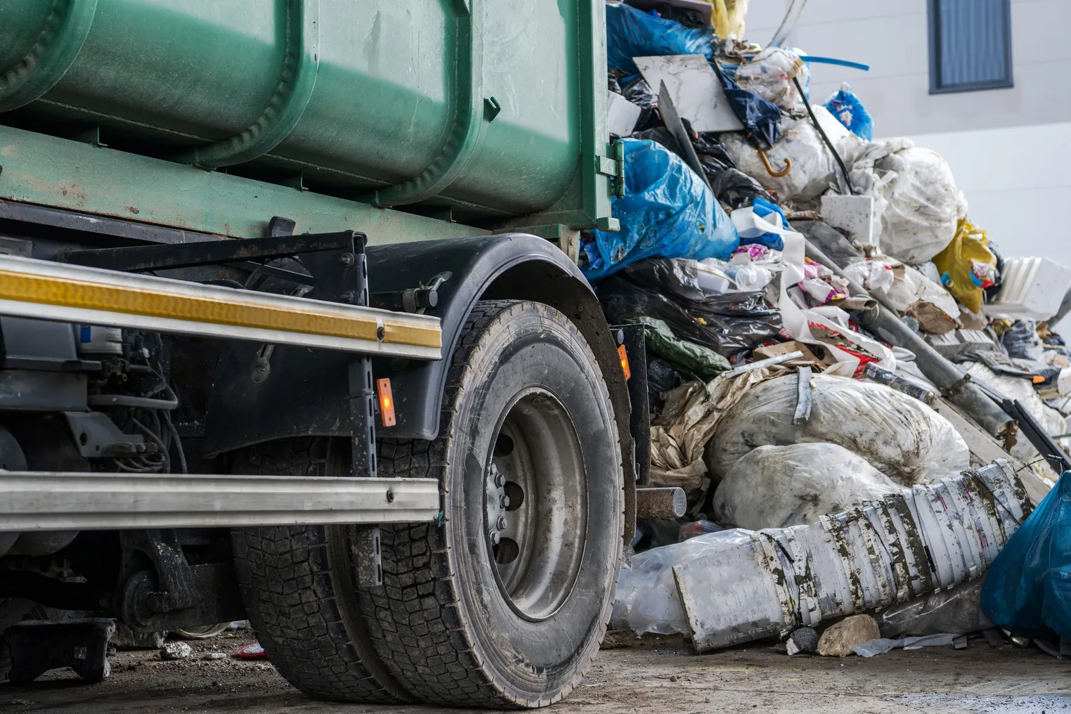 Wheel of trash truck next to pile of garbage and recycling