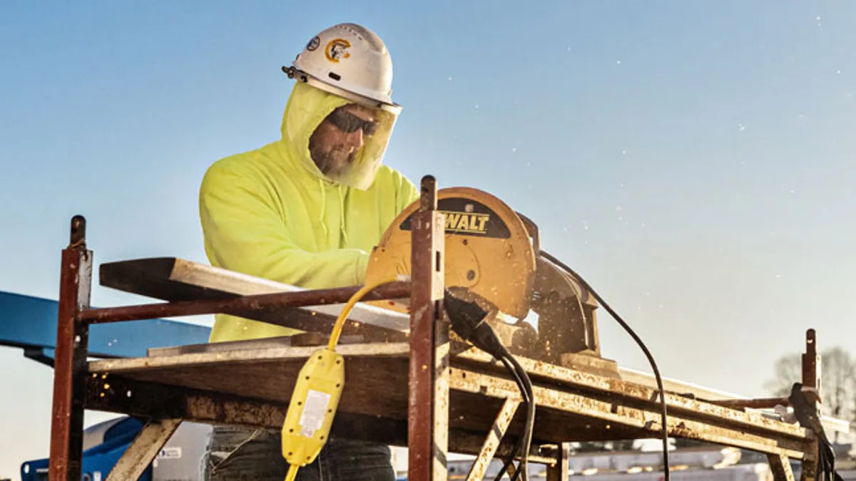 Construction worker using a power tool to saw wood