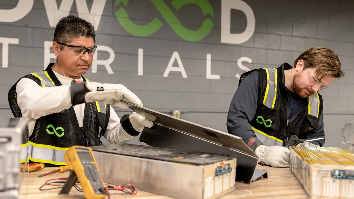 Workers disassemble electronics at a table at Redwood Materials