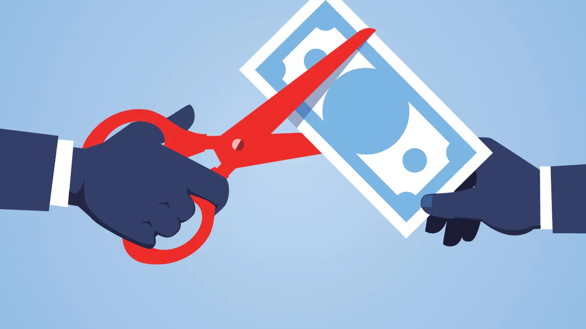 Hand holding scissors to cut banknotes