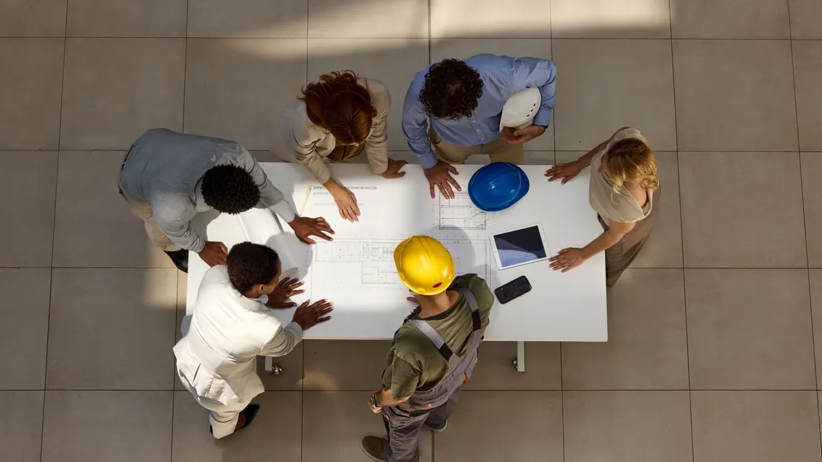 An aerial view of a group of construction professionals having a meeting over drawings.