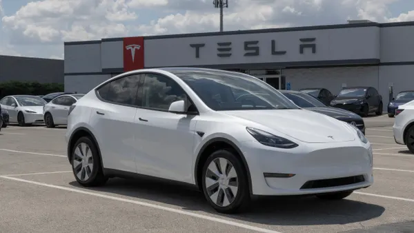 White Tesla car in front of a Tesla dealership.