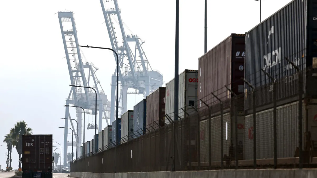 A truck drives past a row of containers on rail cars.