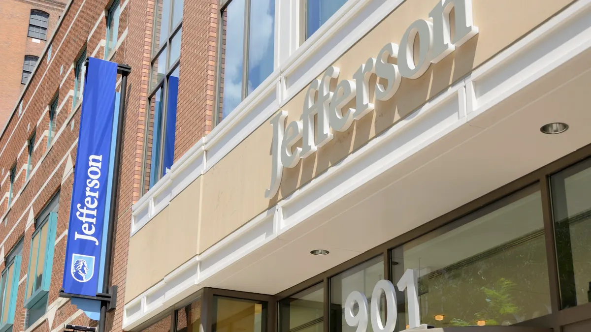 The facade of Thomas Jefferson University hospital, featuring a flag with a logo and the address.