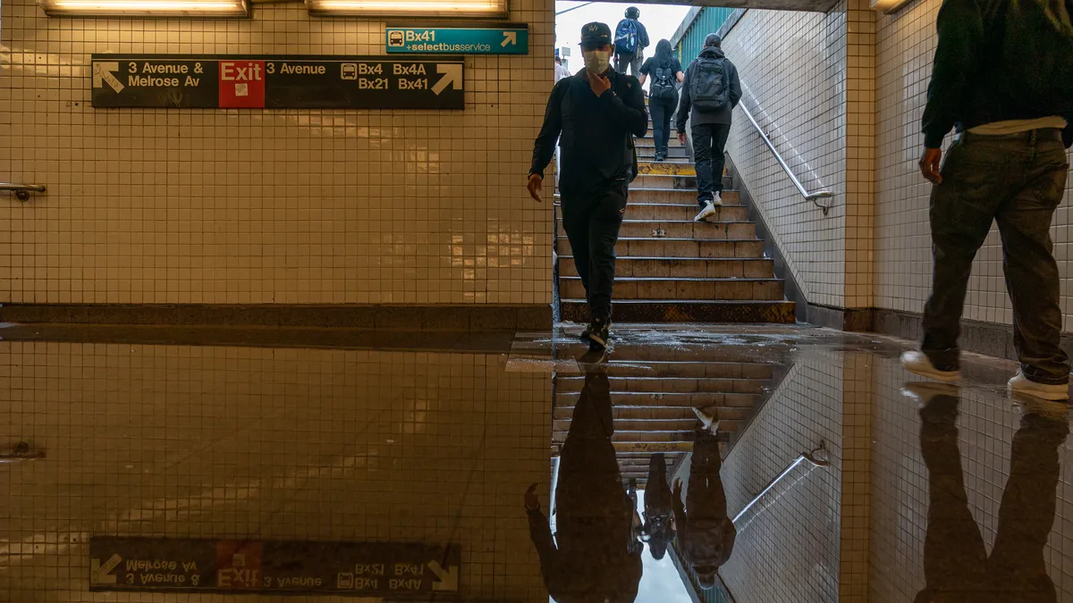 Commuters walk into a flooded 3rd Avenue/149th St. subway station amid disrupted service due to extremely heavy rainfall from the remnants of Hurricane Ida on September 2, 2021, in NewYork City.