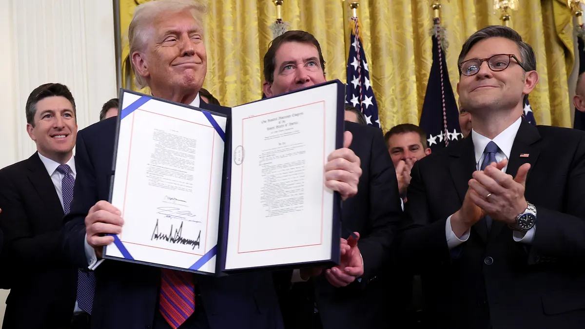 President Trump holds up document with House Speaker Johnson and others behind him.