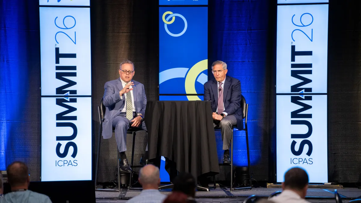 Two men speaking on stage at an accountants conference