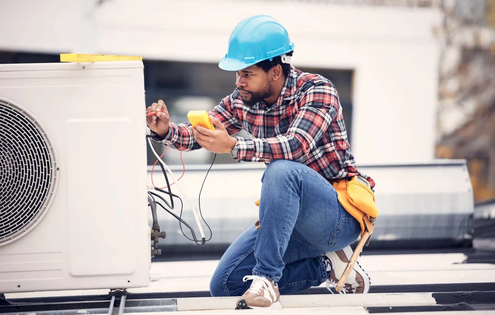 An electrical services contractor is seen working on an electrical power generator to repair an air conditioner.