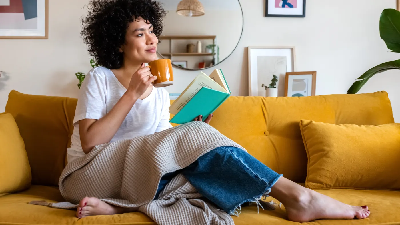 A person sitting on their couch reading a book.