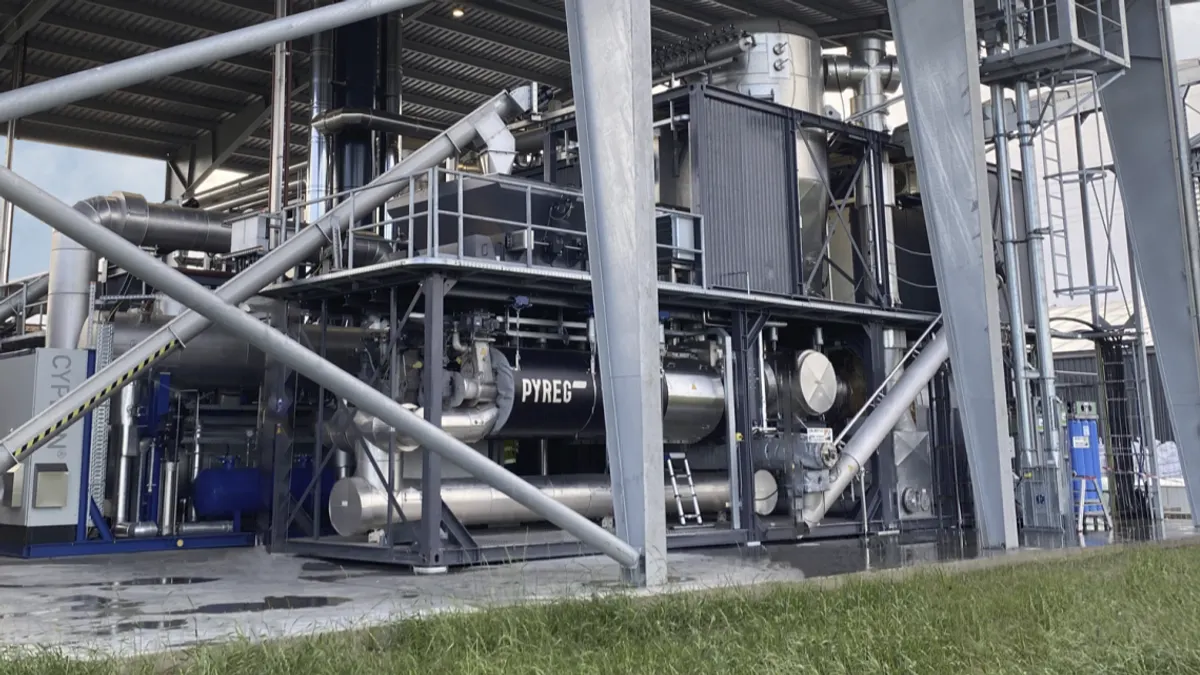 A complex industrial facility in an outdoor shed with the name "Pyreg" printed on the side of a tank.