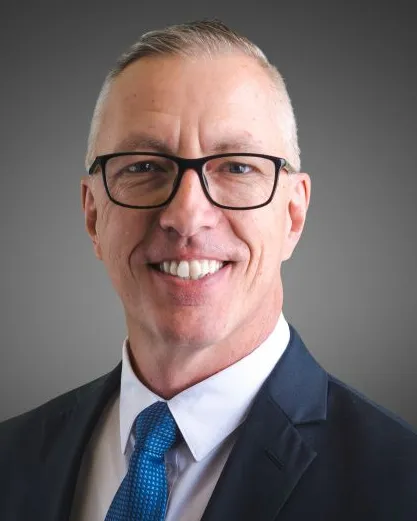 Headshot of a man with white hair in a suit.