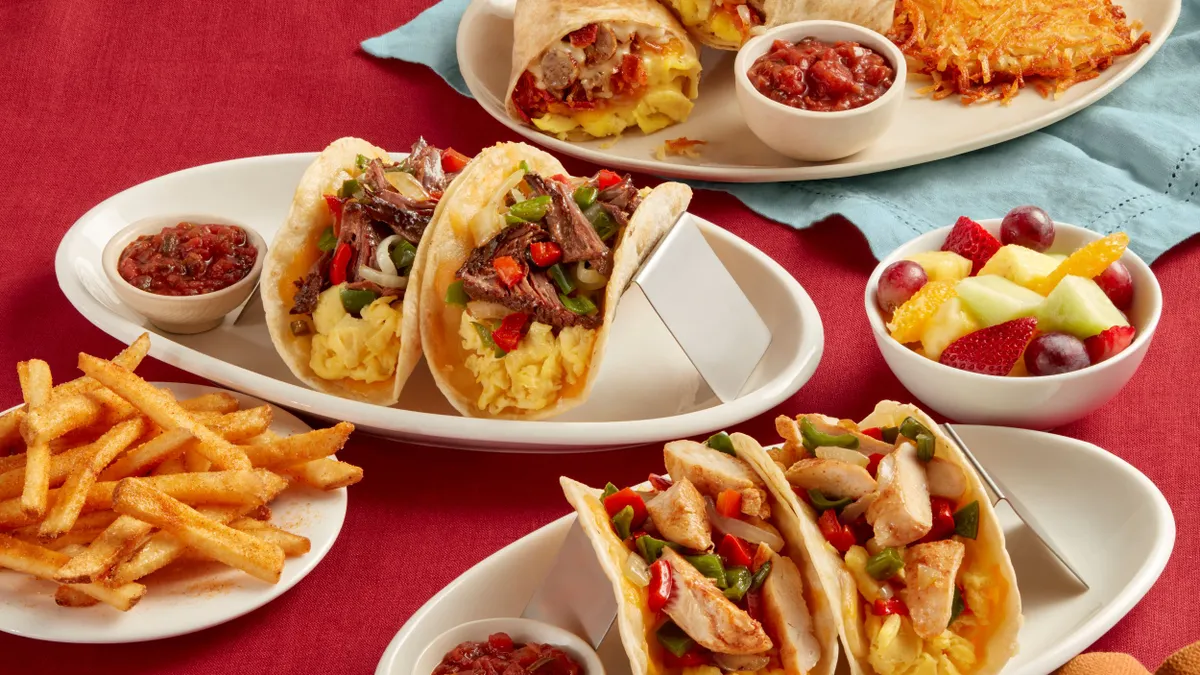 Tacos and a burrito made by IHOP on plates against a red table cloth.