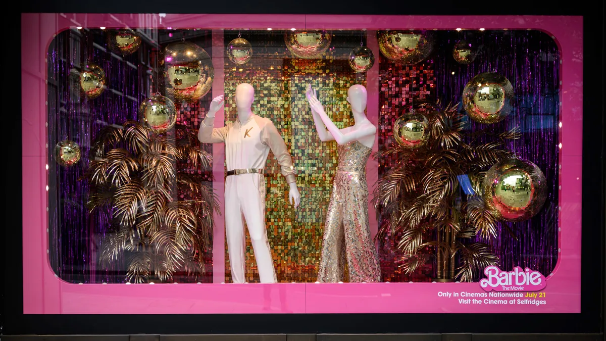 A view of the Selfridges window display features Barbie movie costumes and gold Christmas ornaments.