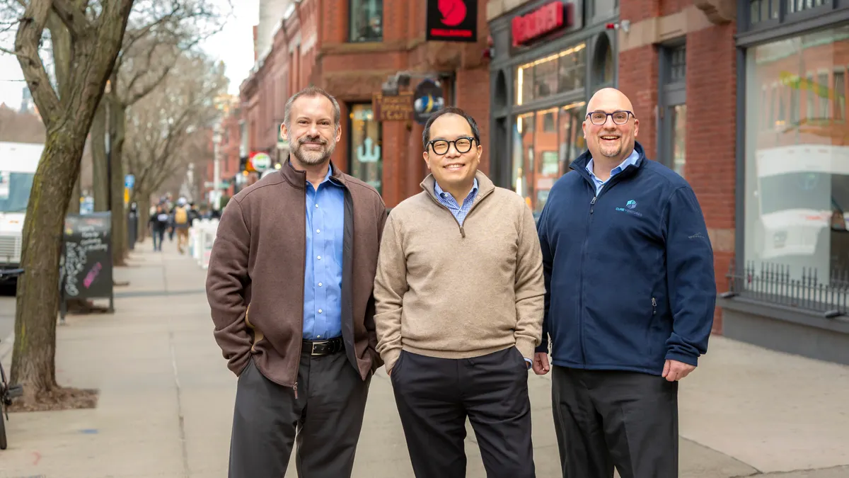 Three business men stand on a city street for a photo