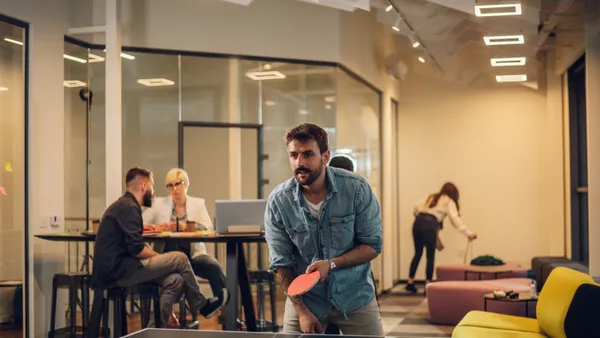 An employee plays table tennis in a break room.