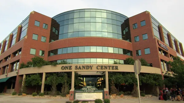 A large brick office building with a sign out front reading "One Sandy Center."