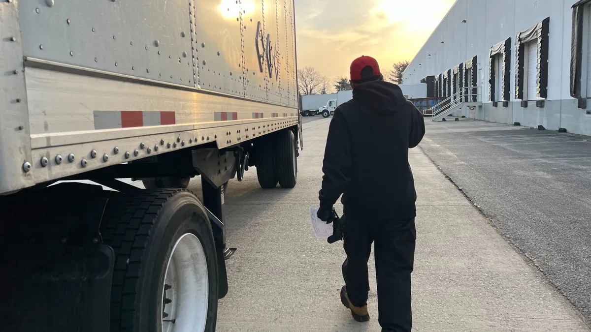 Mitchell walks next to his truck during a delivery with the morning sun peaking through clouds.