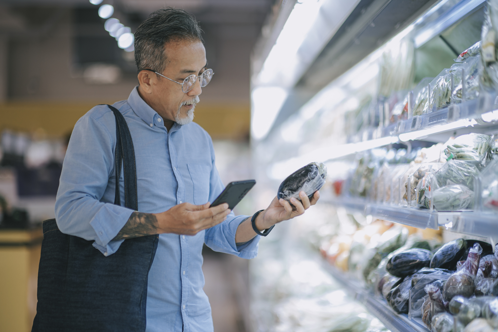 Person shopping with phone in the produce aisle at a grocery store