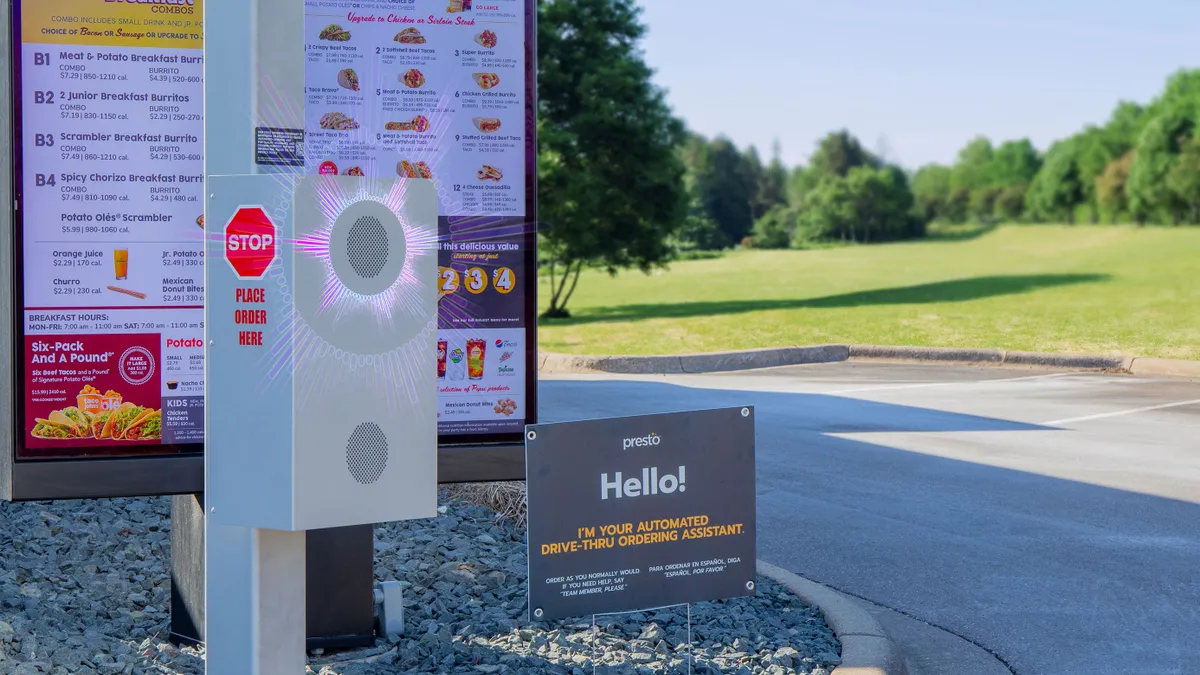 A drive-thru menu board with a speaker box at Taco John's