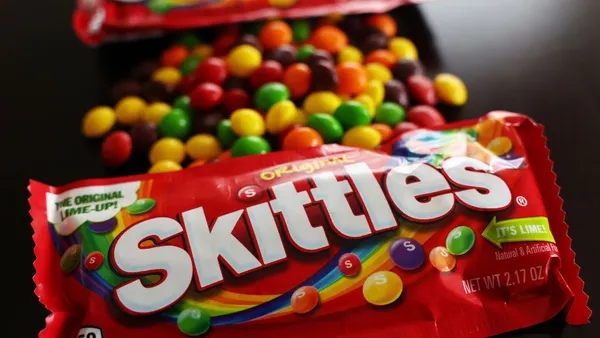 A package of Skittles sits on a table.