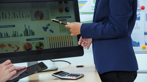 Two young businesswomen sit at a table, engaged in a meeting.examine graphs and discuss capital investment strategies, showcasing their expertise and collaborative approach to business growth.