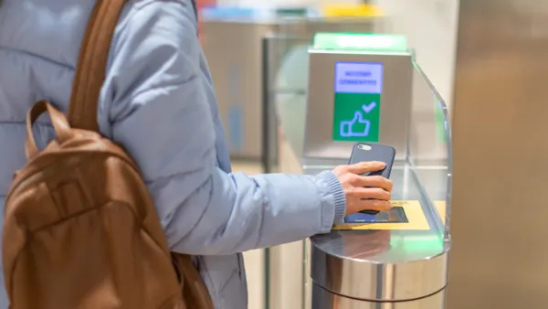 A worker uses their smartphone to gain access at a turnstile.