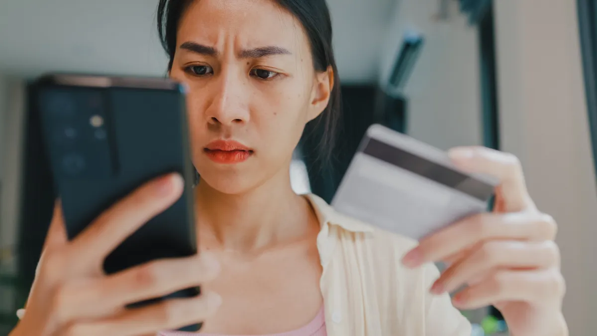 Close-up of a woman holding a smartphone and credit card and feeling upset