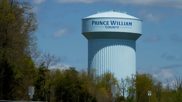A large water tower with the words “Prince William County” painted on it rises above the surrounding trees.