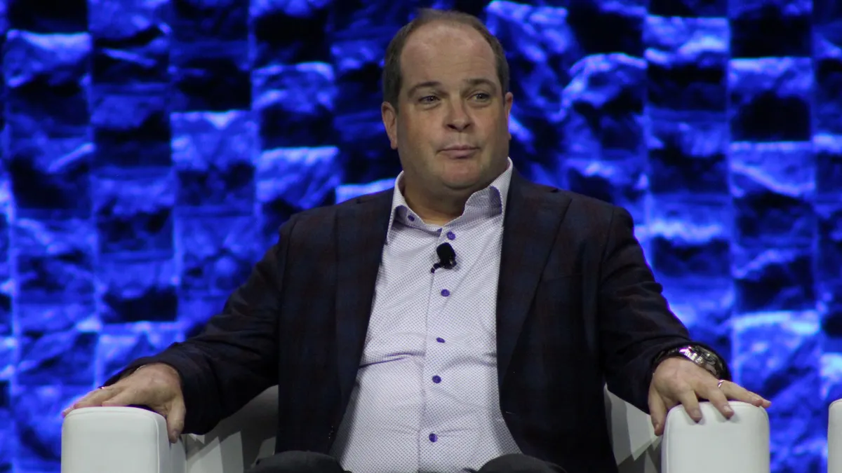 A person sits in a white chair and looks to the side.