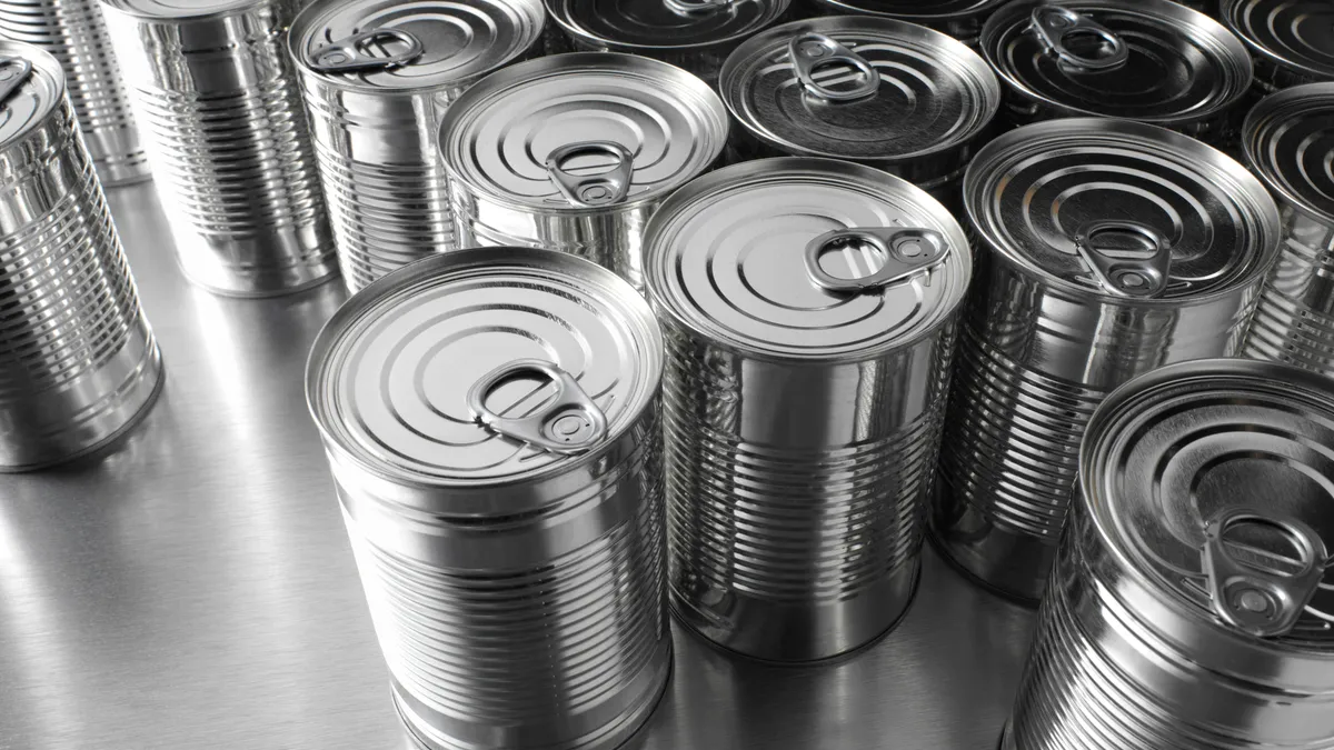 More than a dozen labelless, silver-colored steel food cans grouped together.