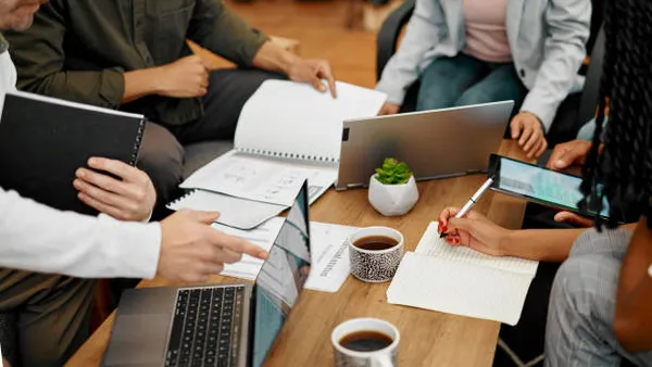 Closeup shot of a group of unrecognisable businesspeople going through paperwork together in an office.