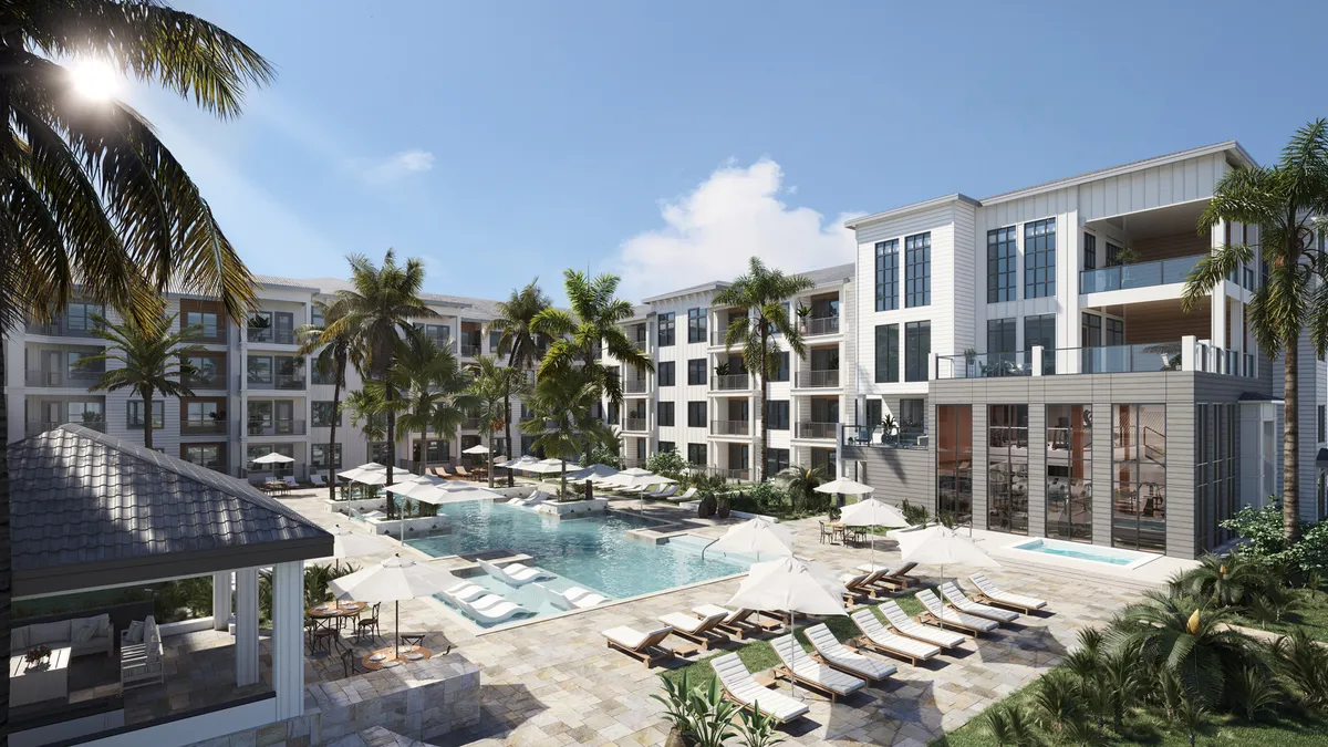 A pool surrounded by palm trees in the courtyard of a mid-rise building.