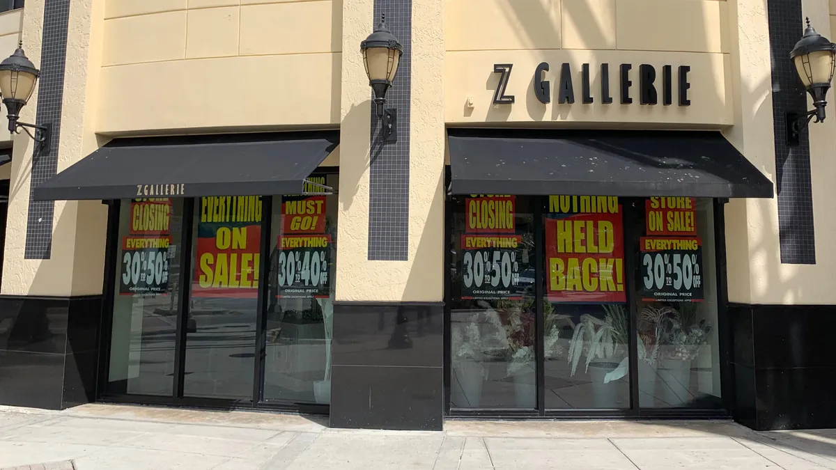 Three lanterns adorn a storefront with sale signs in the windows.