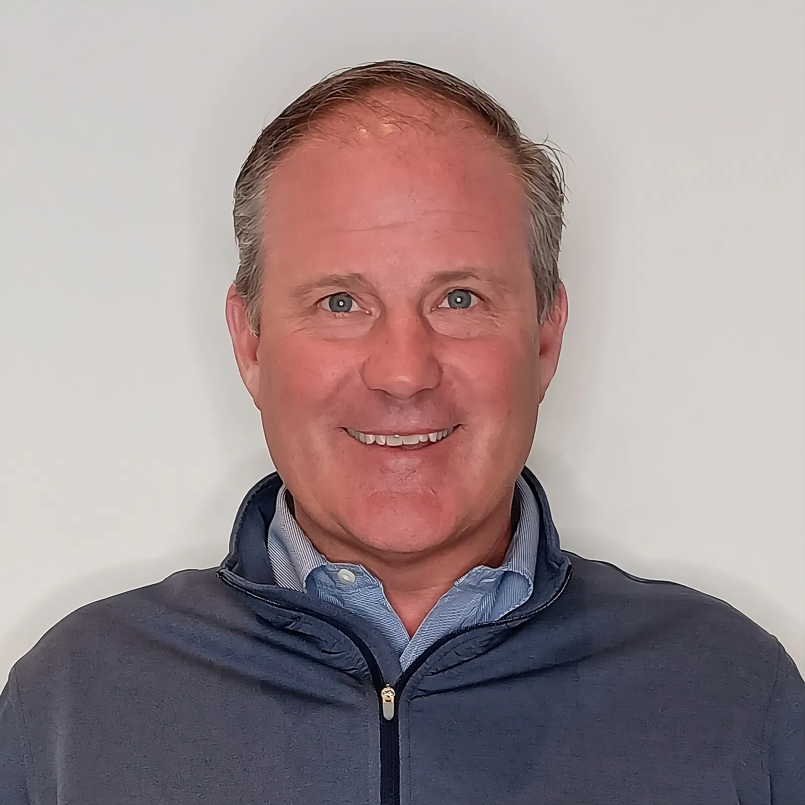 A professional headshot of Tom Dine.