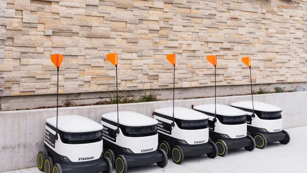 Five delivery vehicles outside of a store.