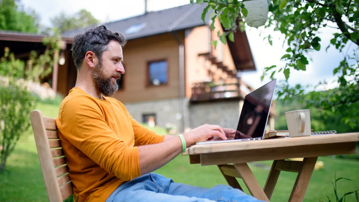 Man working on a laptop in his yard.