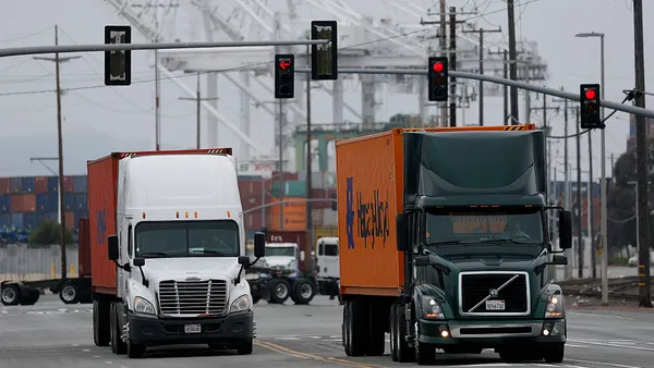 Trucks carrying shipping containers pass through traffic lights.