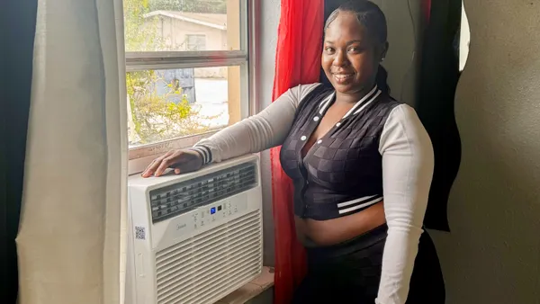 A person standing next to a window air conditioner.