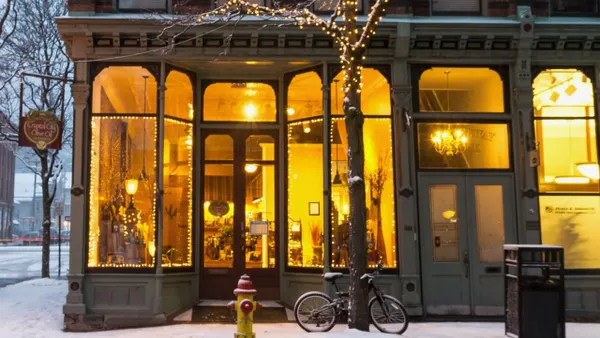 A corner store at dusk during winter, with a bike out front in the snow.