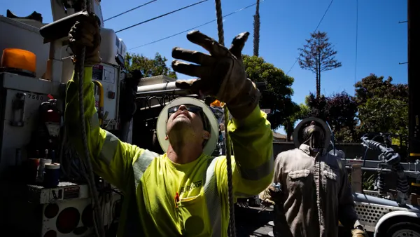 A utility worker in a hard hat looks up