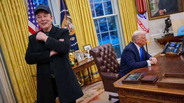 Elon Musk stands, Donald Trump sits in the Oval Office