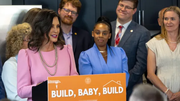 A person stands and speaks at a podium surrounded by other people.